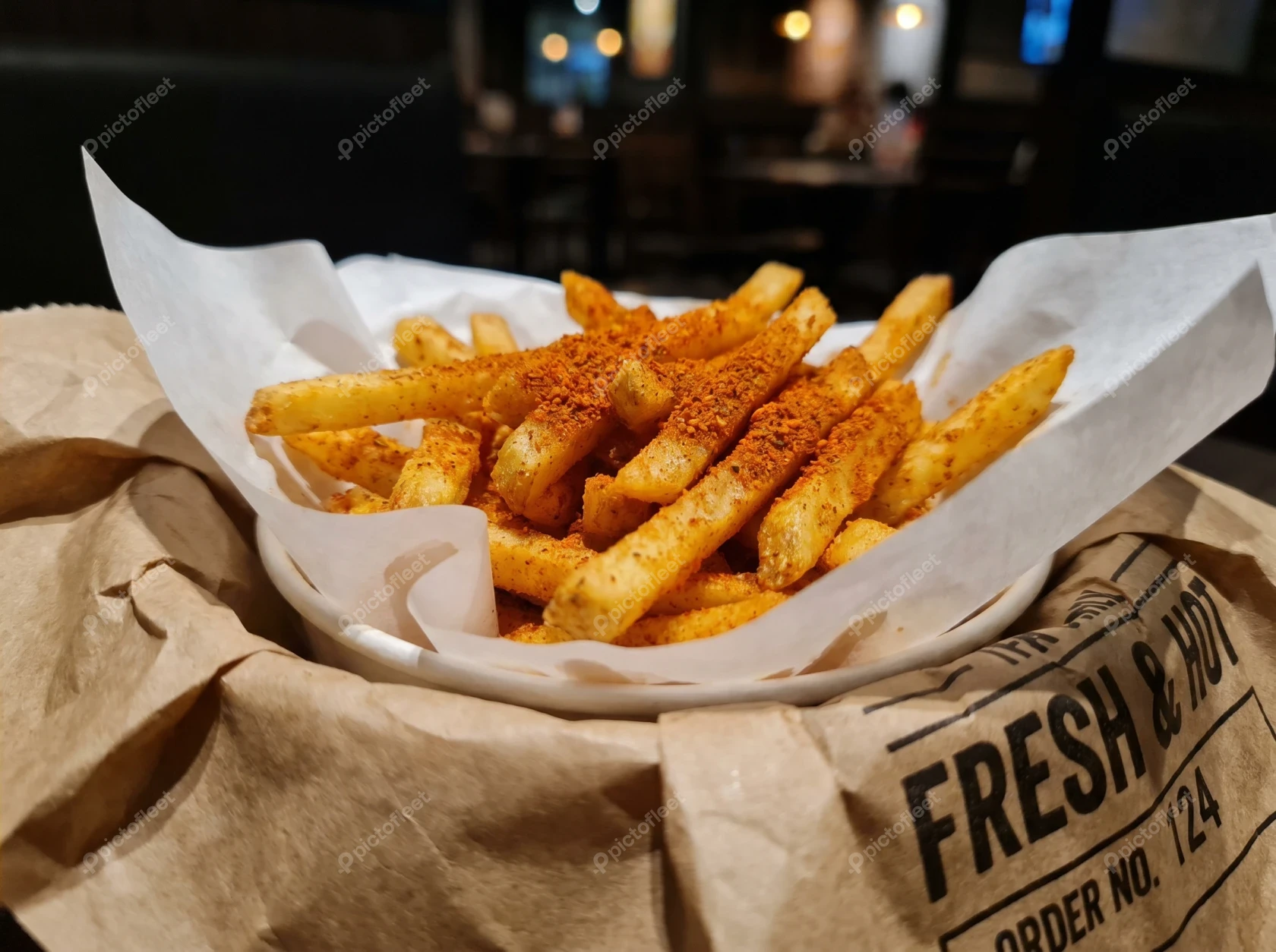 Crispy seasoned french fries in a paper-lined bowl