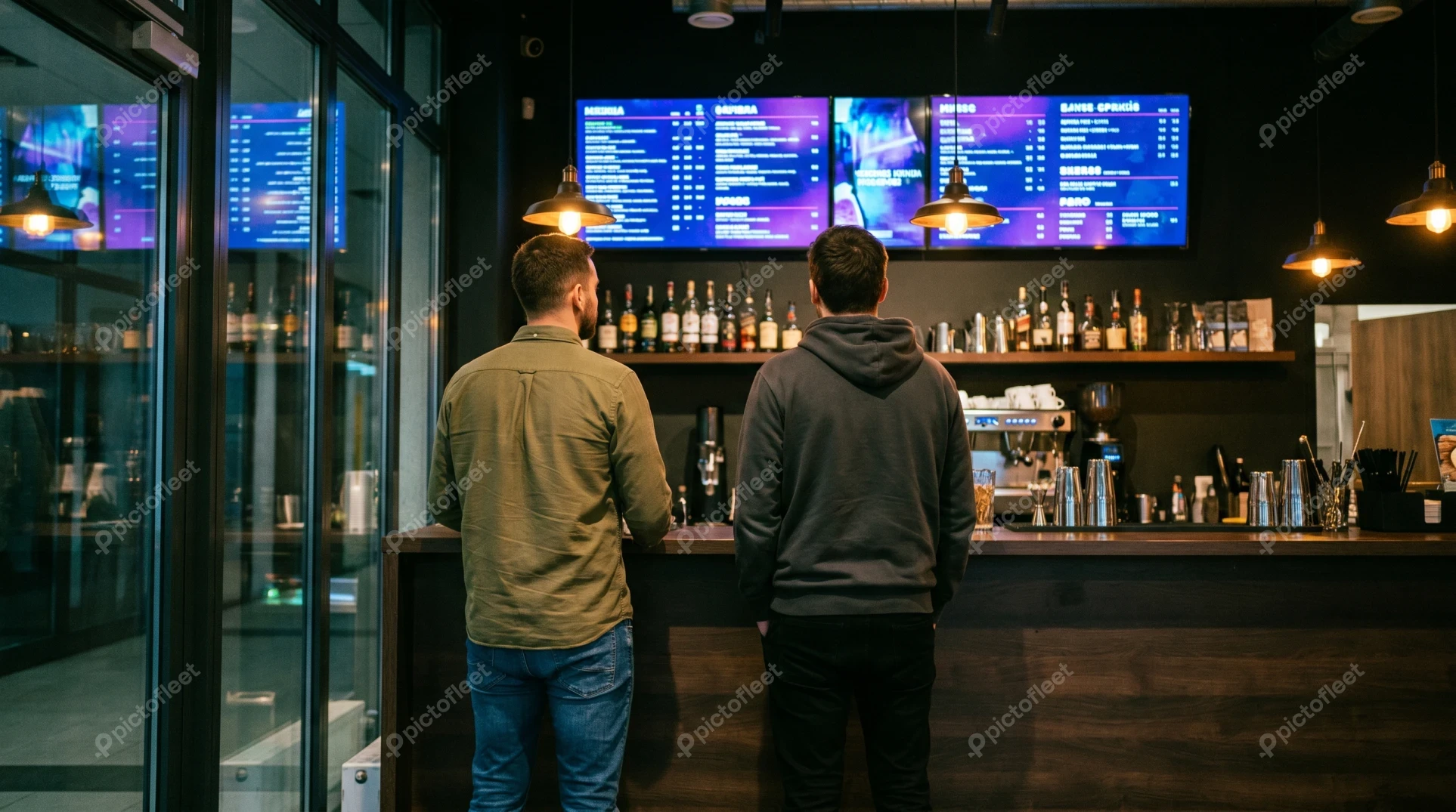 Two men standing at a bar looking at menu board