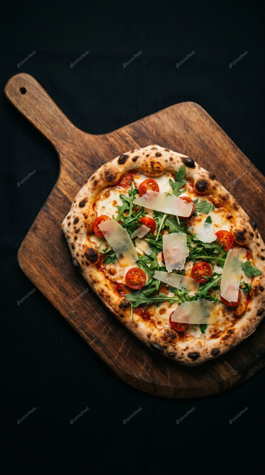 Neapolitan pizza with arugula and cherry tomatoes on wooden peel