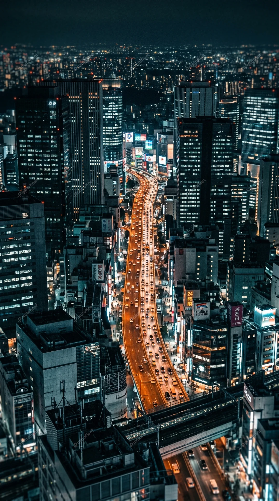 Aerial view of illuminated city skyscrapers and highway at night