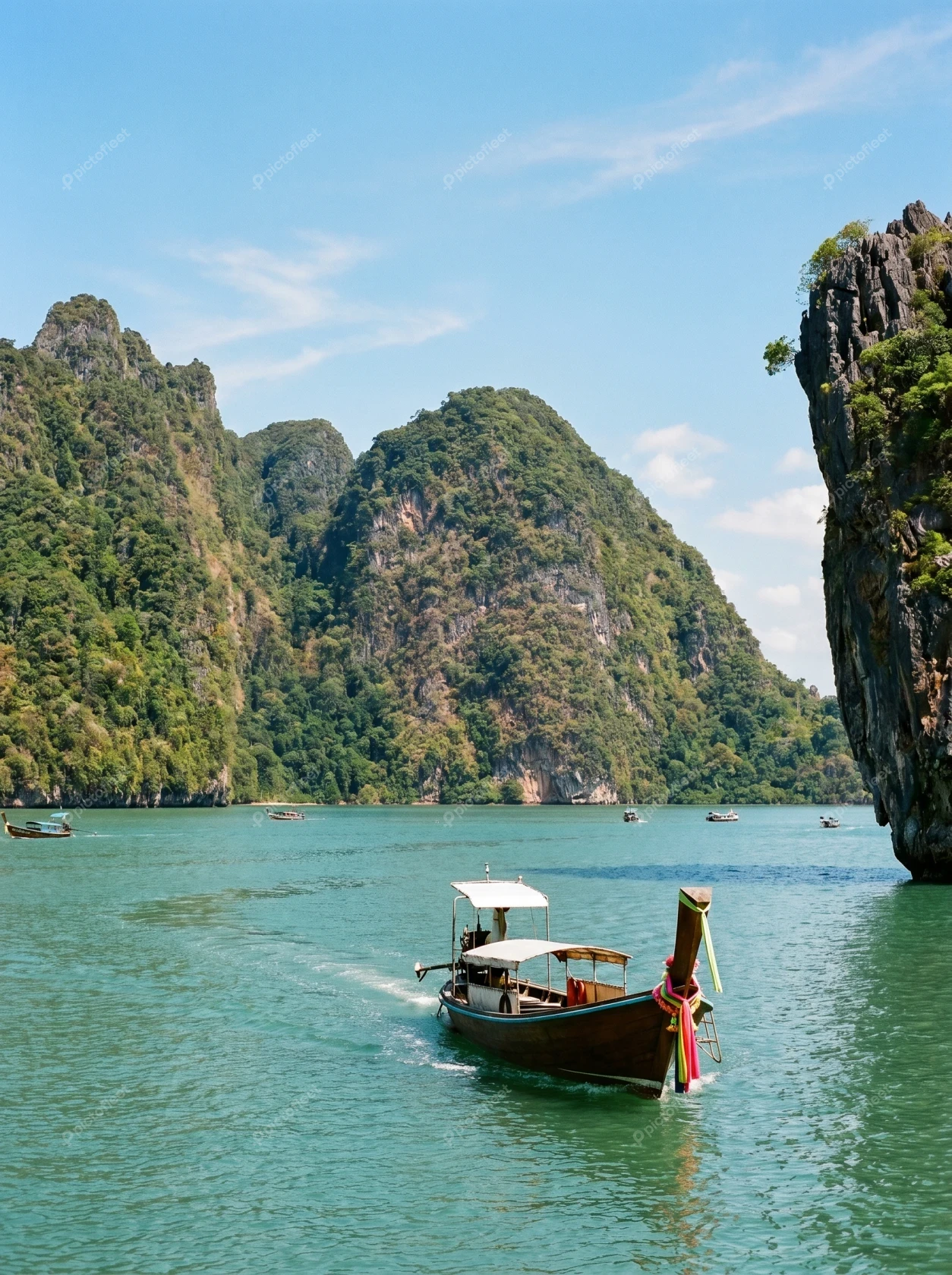 Thai longtail boat sailing past lush tropical limestone islands