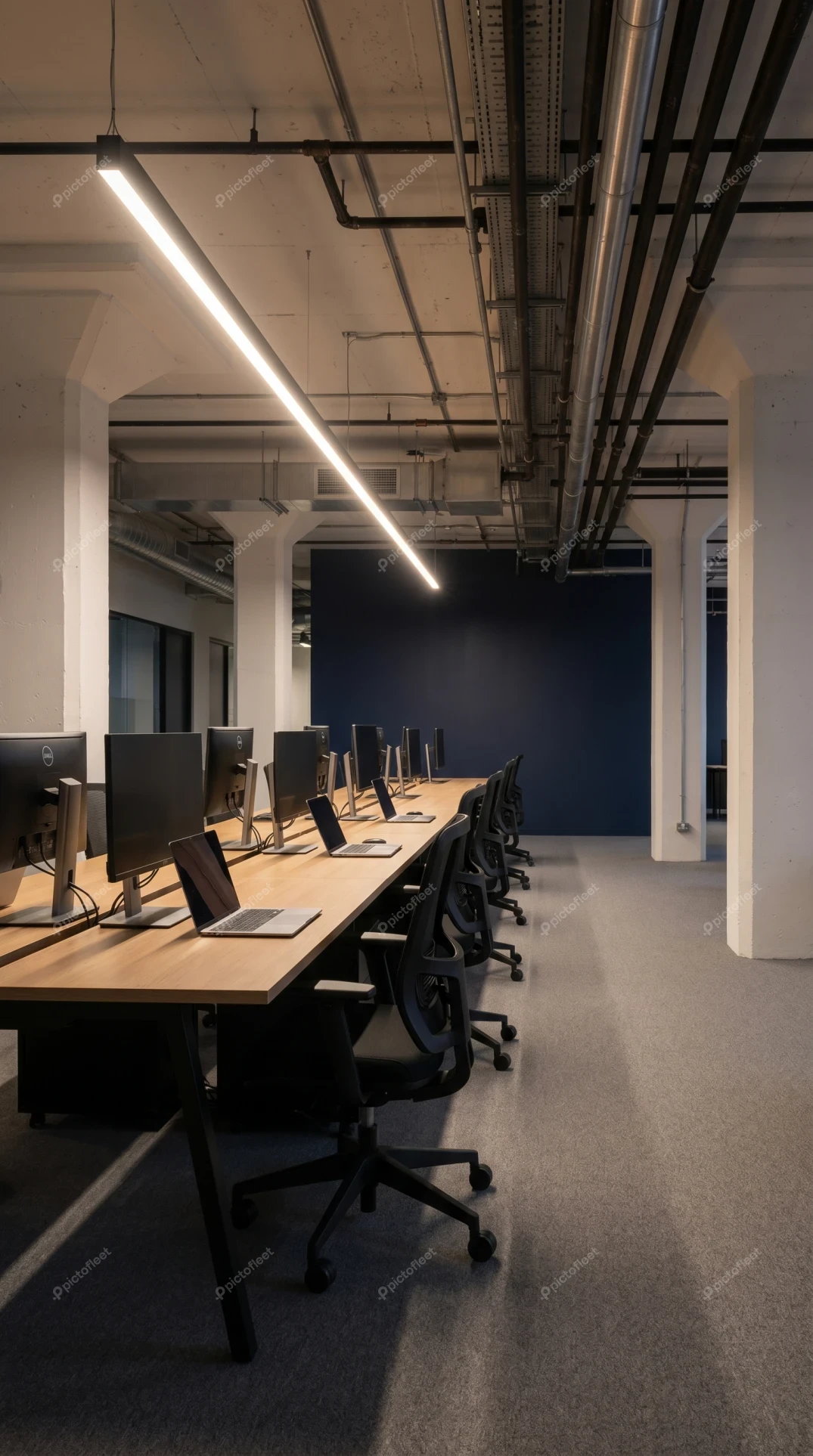 Modern industrial open plan office with rows of workstations