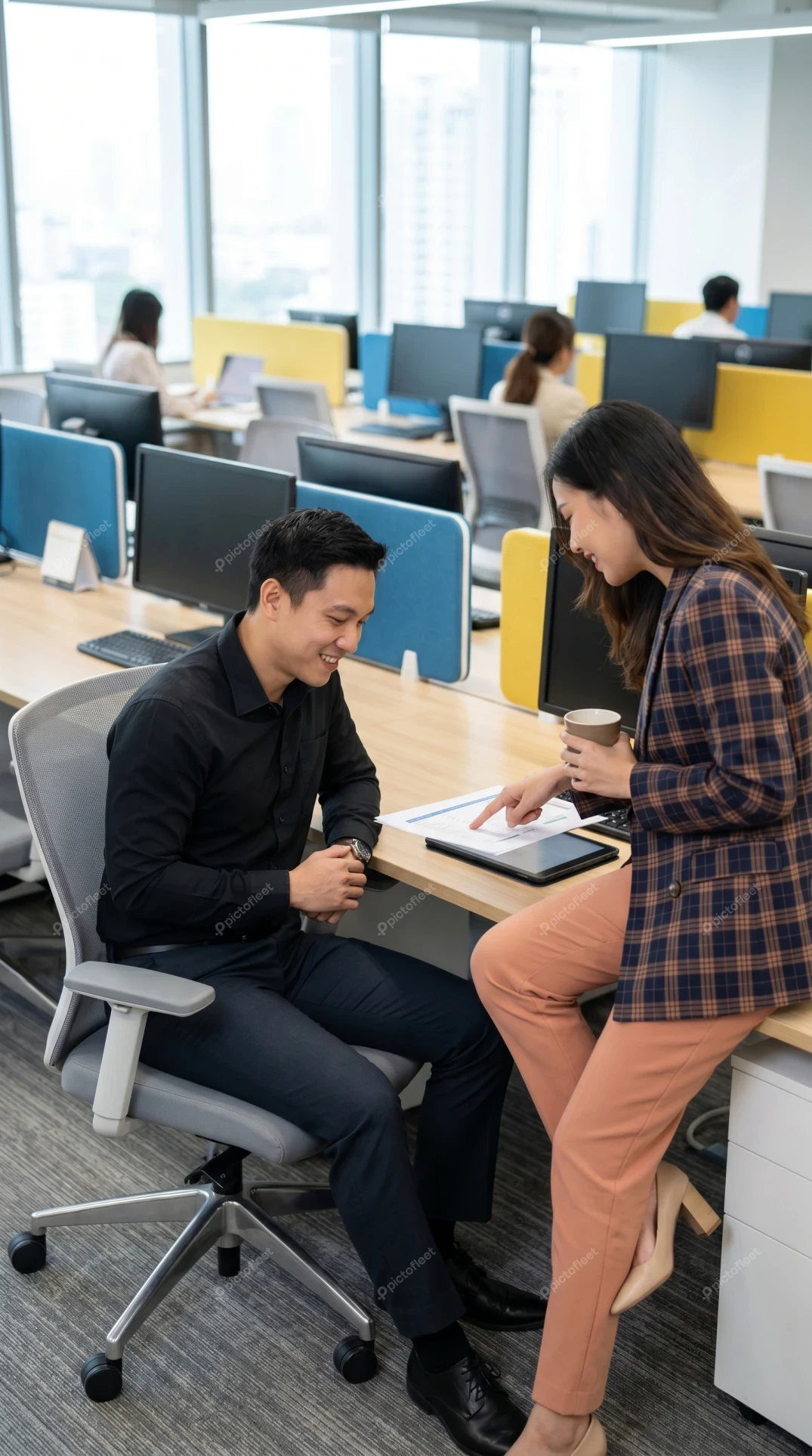 Two professional coworkers discussing work at an office desk