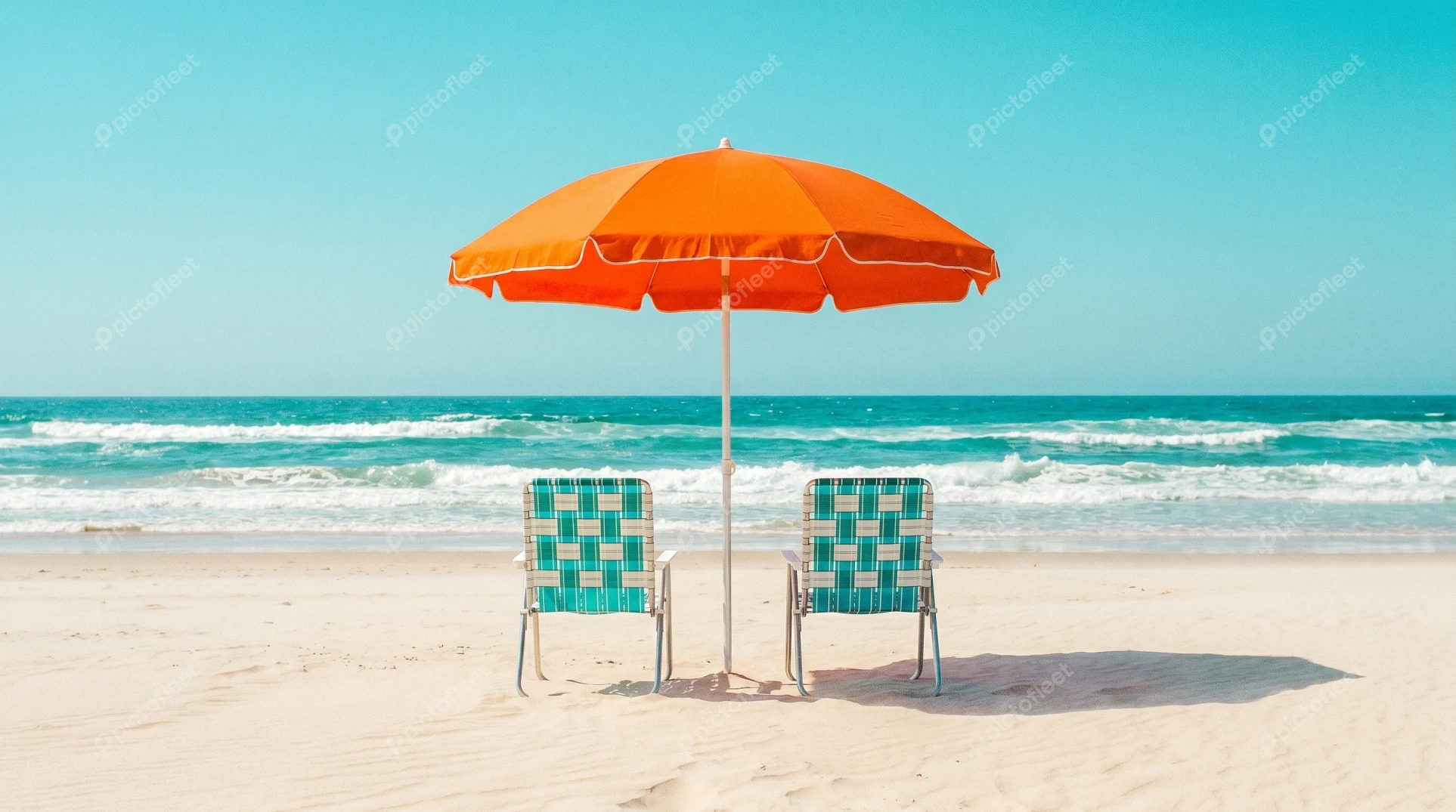 Orange beach umbrella and chairs on a sunny sandy shore