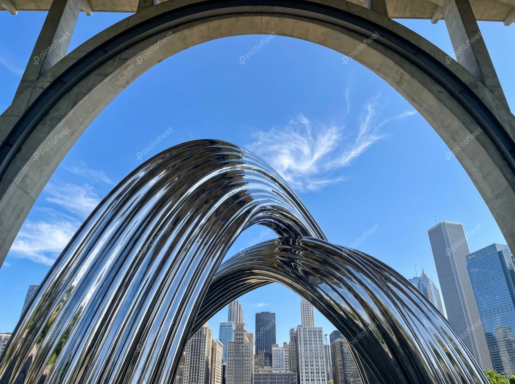 Reflective stainless steel sculpture framing the Chicago skyline under blue sky