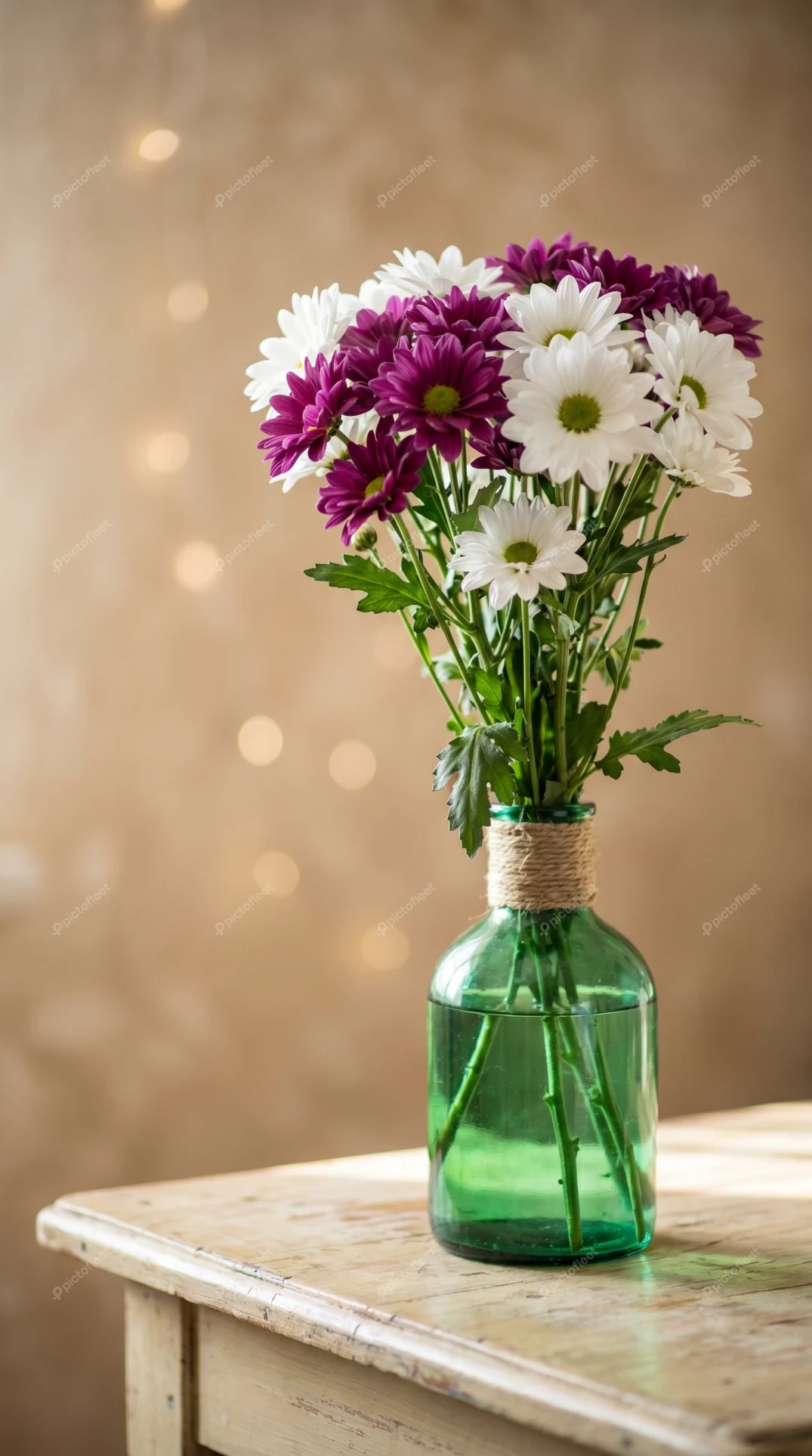 Purple and white chrysanthemums in a green glass vase