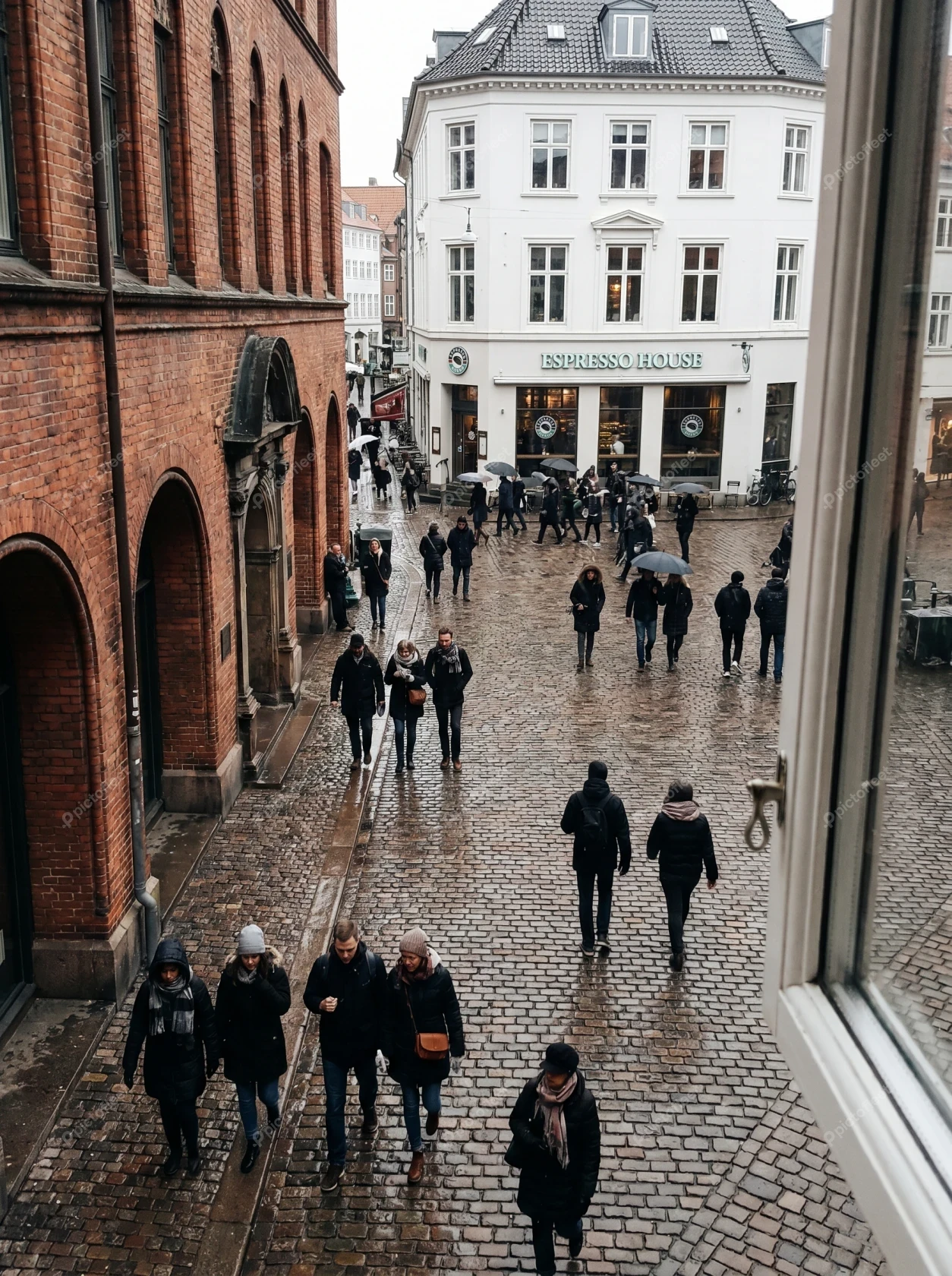 People walking on a wet cobblestone street in European city