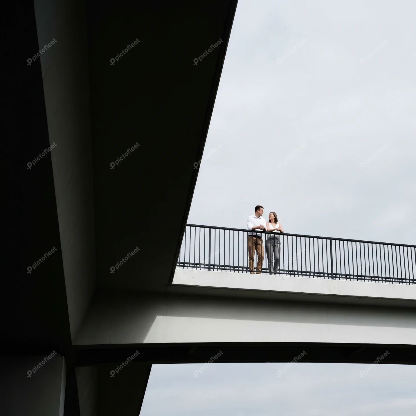 Couple on bridge framed by modern architectural shadows