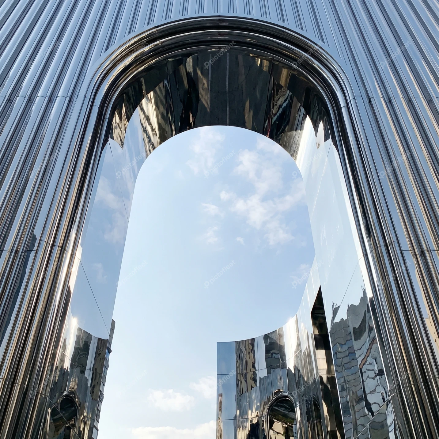 Modern reflective chrome archway under a clear blue sky