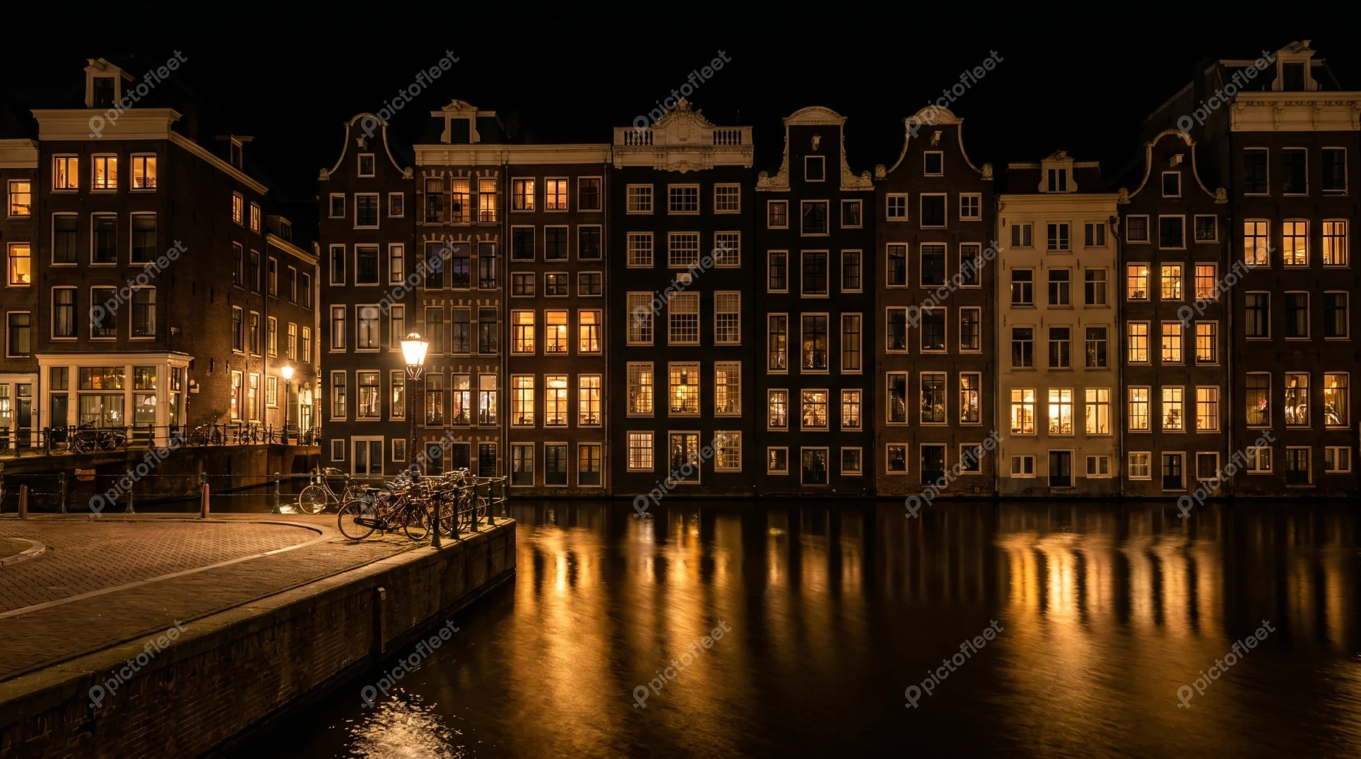 Traditional illuminated canal houses in Amsterdam at night