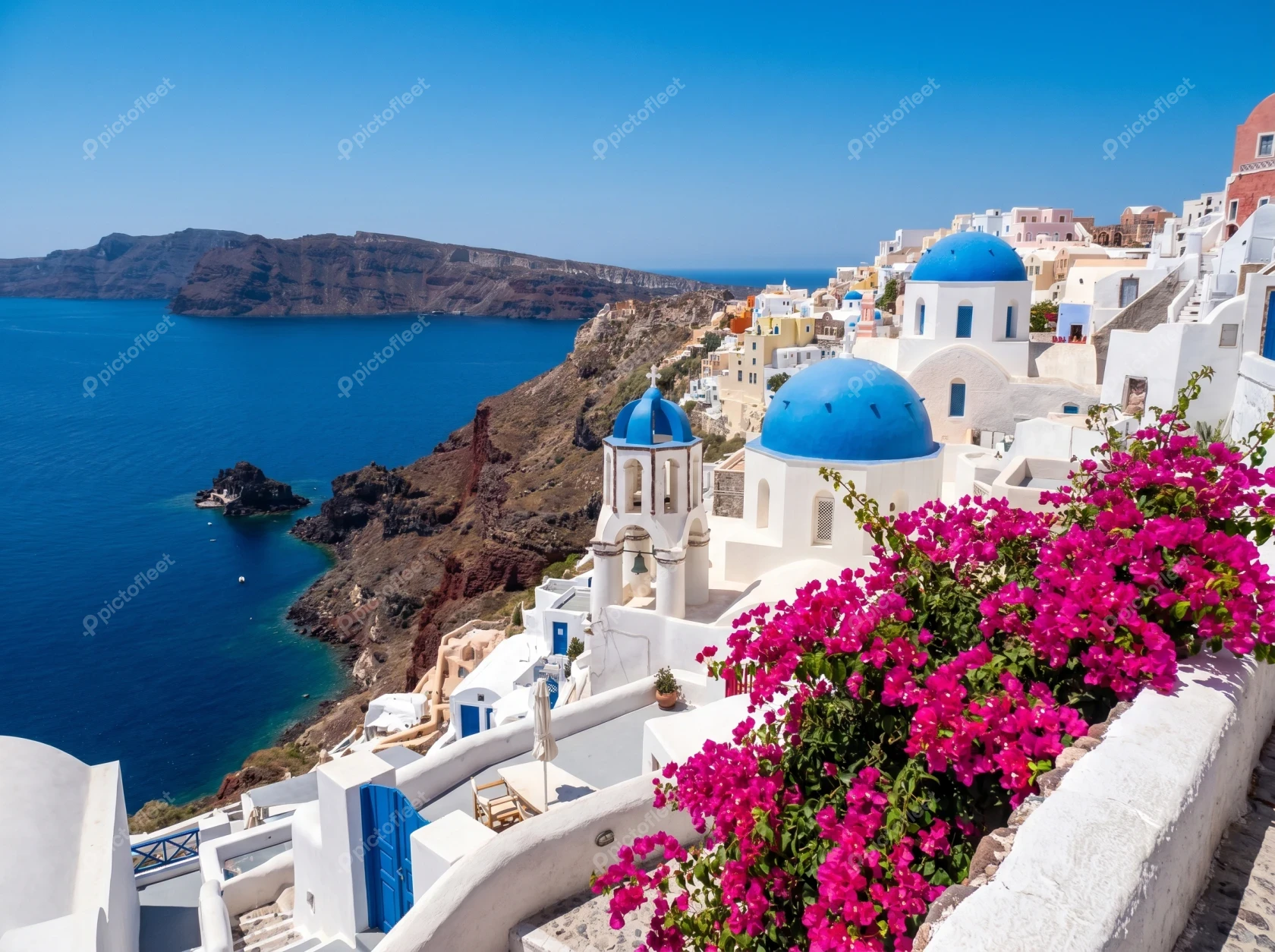 Santorini island with blue domed churches and pink bougainvillea