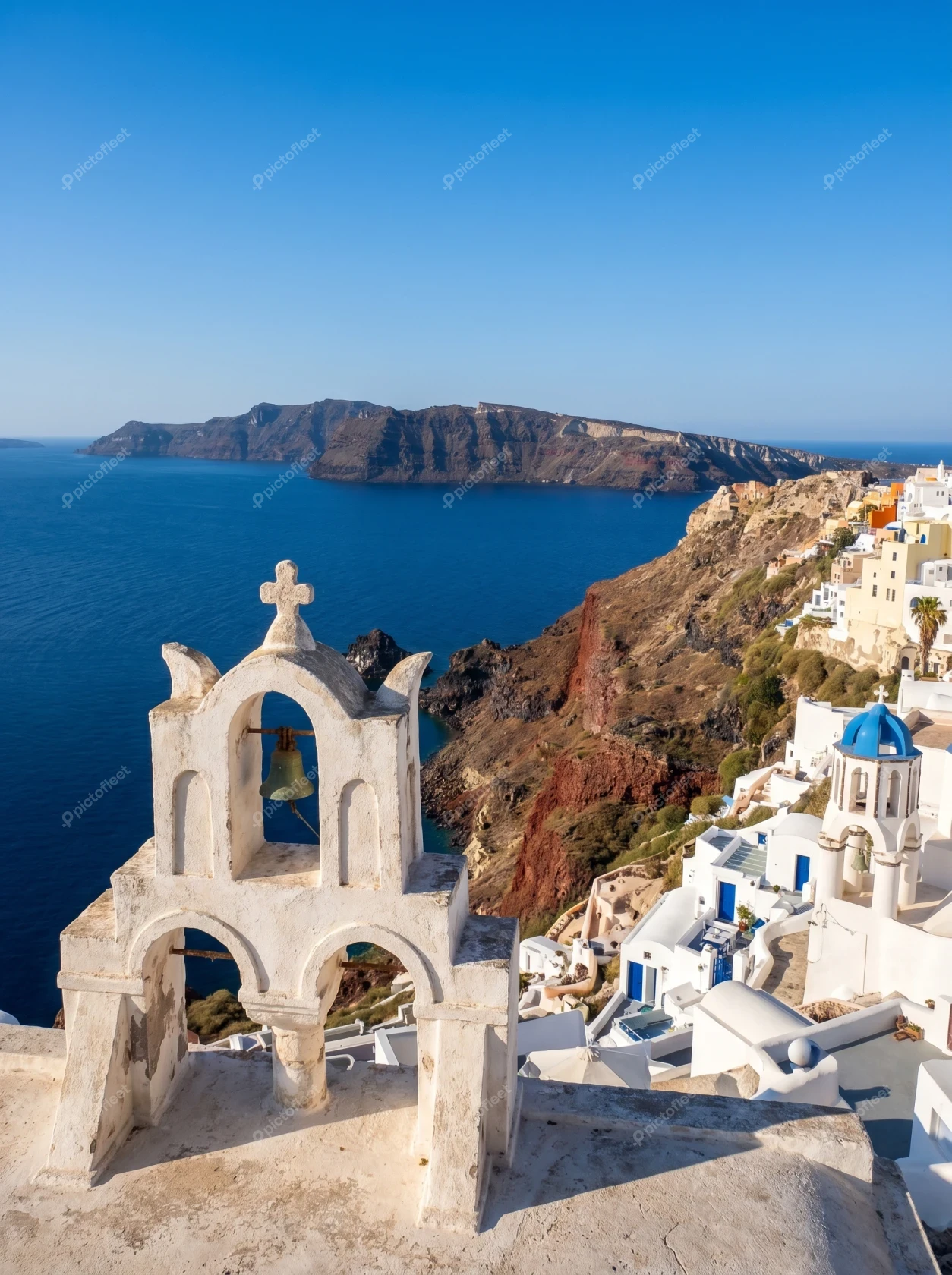 White church bell tower overlooking Oia caldera in Santorini