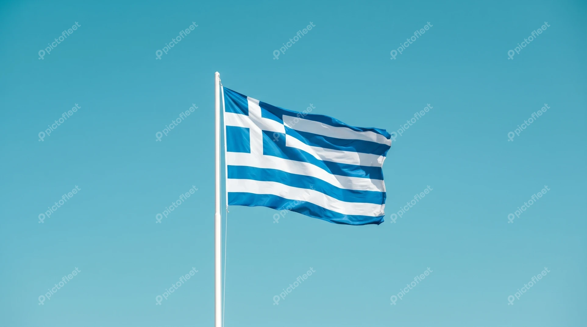 The Greek national flag waving against a clear blue sky